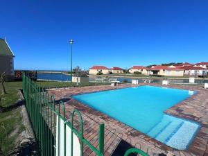 a large swimming pool in a yard with a fence at Fijnbosch Villa at Claptons in Jeffreys Bay