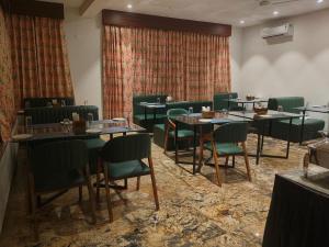 乌代浦MAYA'S MANOR - A Luxury Lake View Boutique Hotel的有桌子和绿色椅子的餐厅