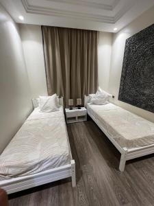 two beds in a room with two tables at Appartement de charme au Vizir Resort in Dar Caïd Layadi