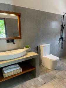 a bathroom with a sink and a toilet and a mirror at Bloom Beach Villa in Batigama