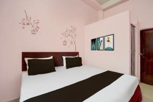 a white bedroom with a large bed with black pillows at Hotel O Royal Stay in Bhilai