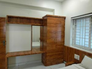 a room with a mirror and a wooden cabinet at Hotel O New anugraha deluxe in Kulurkudrū