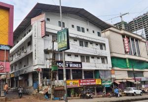 a tall white building with signs on the side of it at Hotel O New anugraha deluxe in Kulurkudrū