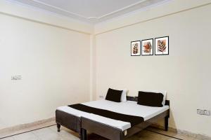 a bed in a room with a white wall at Hotel O Radha Residency in Badarpur