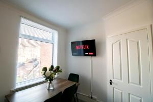 a room with a table and a television on the wall at Kingley Court By Greenstay Serviced Accommodation - A Newly Refurbished 2 Bed Flat In Gateshead - Ideal For Contractors - Business Travellers & Relocations - 10 Mins From Newcastle City Centre - Free Parking - Fast Wi-Fi in Gateshead