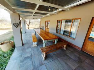 a porch with a wooden table and a bench at Oryx Lodge in Brits
