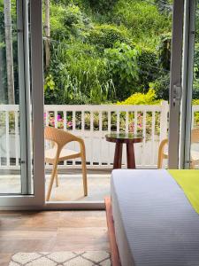 a room with a bed and a table and a balcony at The Green Lodge Kandy in Kandy