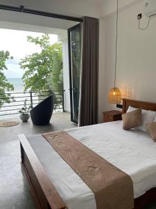 a bedroom with a bed and a large window at Bloom Beach Villa in Batigama