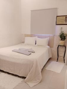 1 dormitorio blanco con 1 cama grande con almohadas blancas en Casa Ilhabela 2 centro a 5 minutos, en Ilhabela