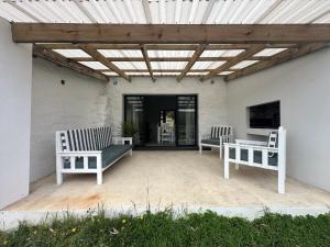 a patio with two benches and a pergola at The Sheperd's Cottage in Joubertina