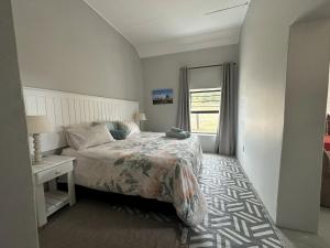 a bedroom with a bed and a table and a window at The Sheperd's Cottage in Joubertina