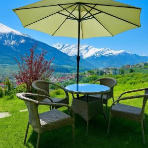 a table and chairs with an umbrella and mountains at Himalayan Crescent 2 Bedroom Luxury independent Villas Manali in Manāli