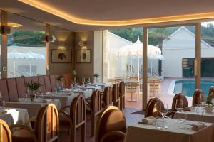 a restaurant with white tables and chairs and a pool at Hôtel Maison Borrèze in Souillac
