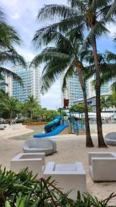 een speeltuin op het strand met palmbomen en een gebouw bij SM Bicutan Miami Flat in Manilla