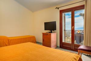 Cette chambre comprend 2 lits, une télévision et une fenêtre. dans l'établissement Il Nuovo Gabbiano, à Cala Gonone