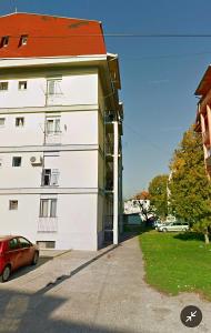 a red car parked next to a white building at Home in Kraljevo
