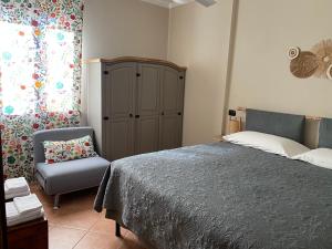a bedroom with a bed and a chair and a cabinet at La Corte di San Rocco in Murazzano
