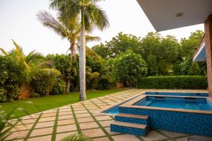 a swimming pool in a yard with a palm tree at Sukoon The घरर in Jodhpur