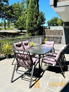 a patio with a glass table and purple chairs at Comfortable & Spacious -2bd 2bth - Braddon in Canberra