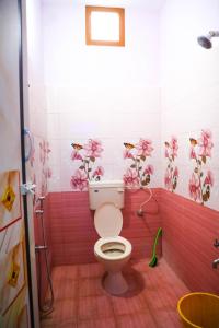 een badkamer met een toilet met roze bloemen aan de muur bij Nandhi home stay in Tiruvannamalai
