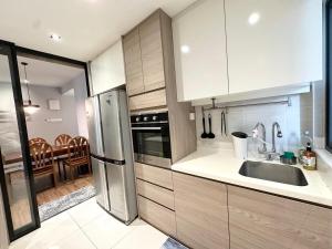 a kitchen with white cabinets and a stainless steel refrigerator at Family Suite -3R2B, Upto8pax, 2 Car Park, Netflix, Nearby The Mines, UPM in Serdang