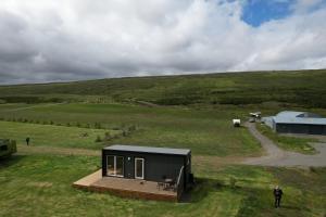 una pequeña casa negra en un campo verde en Hótel Stuðlagil Canyon, en Egilsstadir