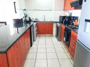 a kitchen with brown cabinets and a white tile floor at Kuta Beach 7 in Margate