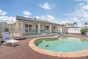 una casa con piscina en una terraza de madera en Spacious waterfront home with pontoon, pool, BBQ, en Kawana Waters