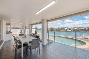 comedor con mesa, sillas y piscina en Spacious waterfront home with pontoon, pool, BBQ, en Kawana Waters