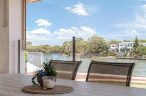 una mesa con sillas y vistas al agua en Spacious waterfront home with pontoon, pool, BBQ, en Kawana Waters