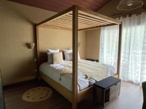 a bedroom with a canopy bed and a television at Domaine Coul'Eau in Eaunes
