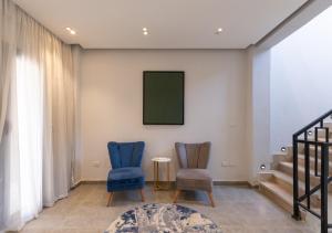 two blue chairs in a living room with a green screen at The Green Escape 4BR Villa By Travelholic in Cairo