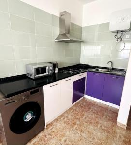una cucina con armadietti viola e forno a microonde di GoBeyond - Serra T2 a Porto Novo