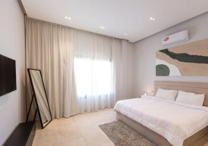 a bedroom with a white bed and a window at The Green Escape 4BR Villa By Travelholic in Cairo +22 photos