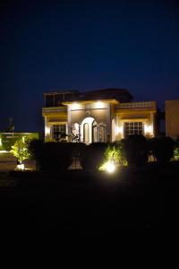ein nachts beleuchtetes Haus mit Licht in der Unterkunft Sandhu farmhouse in Lahore