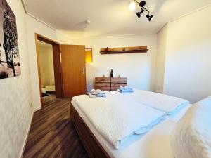 a bedroom with a white bed and a wooden floor at Moritz Apartments - Am Rieseninger Berg 1 in Görmar