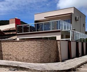 a house with a brick wall and a glass balcony at Casa 51 Piscina 3 suites prox Beto Carrero in Penha