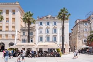 un groupe de personnes marchant dans une rue devant les bâtiments dans l'établissement Riva Luxury Suites, à Split