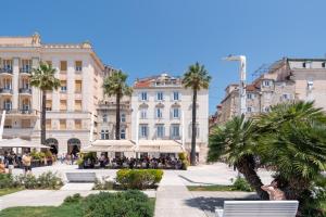 une rue de la ville avec des palmiers et des bâtiments dans l'établissement Riva Luxury Suites, à Split