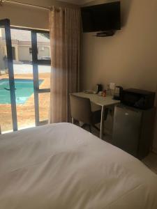 a bedroom with a bed and a table and a window at Divine Boutique Hotel in Rustenburg +23 photos
