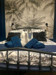 a bed with blue pillows on it with a wall at Chambre bleu Chic et cosy piscine spa petit déjeuner in Varennes Vauzelles
