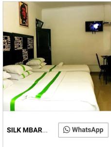 two beds in a room with a tv on the wall at Silk Mbare Guest House in Manzini