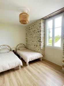 莫南Maison Ganibette, corps de ferme rénové的一间卧室，有两张床和一面石墙