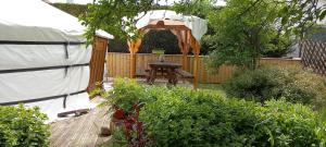 a backyard with a wooden table and a gazebo at yourte d'hotes in Mailley-et-Chazelot