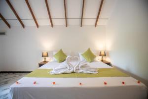 twee witte handdoeken op een bed met twee kussens bij Middle of The Village Sigiriya in Palutawa