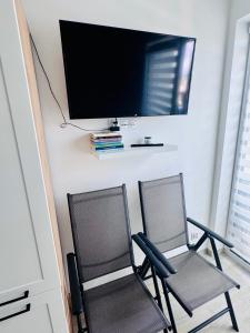 two chairs with a flat screen tv on a wall at Perła Mórz 74 in Sianozety +2 photos