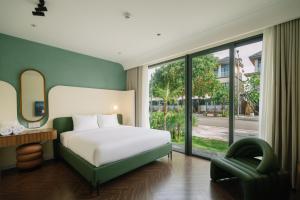 a bedroom with a white bed and a green chair at TRON Villa - Regal Victoria Luxury BT9-09 in Dien Ban +169 photos
