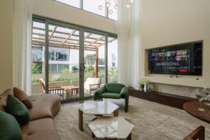 a living room with a couch and a tv at TRON Villa - Regal Victoria Luxury BT9-09 in Dien Ban