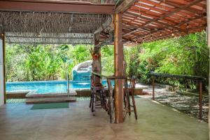 a patio with a table and chairs and a pool at Casa de las Palmas, Residencia Isabella in Parrita