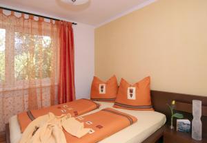 1 dormitorio con 2 camas con almohadas de color naranja y ventana en Haus Hillinger en Salzburgo